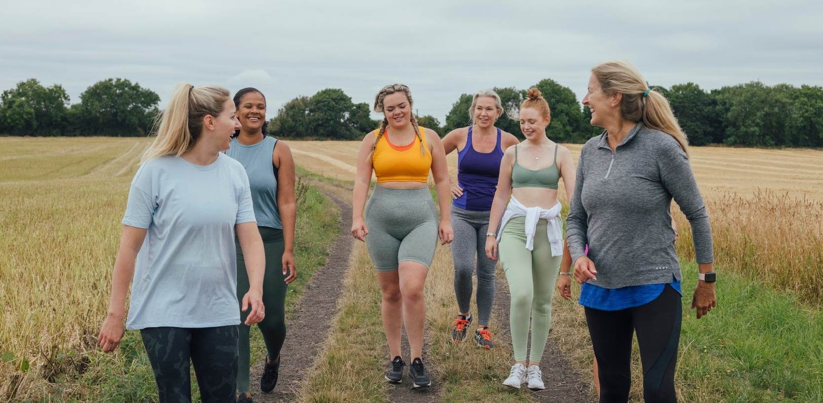 Group of people walking together outdoors on a countryside path. Image represents an active lifestyle, wellness, healthy aging, mobility, recovery, and overall well-being, supporting the benefits of LED light therapy and self-care.