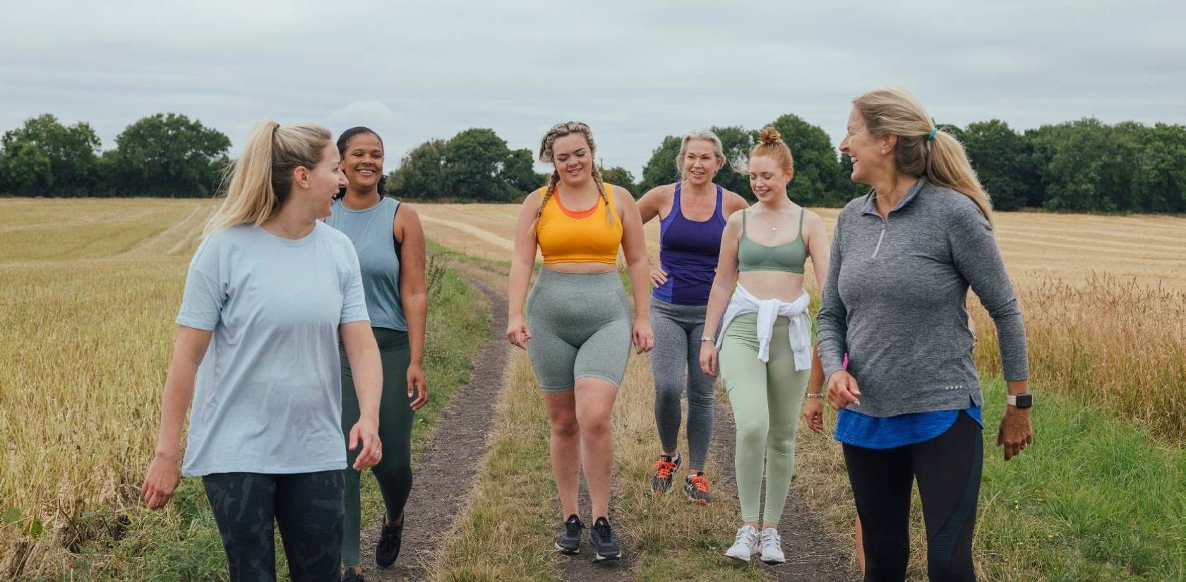 Group of people walking together outdoors on a countryside path. Image represents an active lifestyle, wellness, healthy aging, mobility, recovery, and overall well-being, supporting the benefits of LED light therapy and self-care.