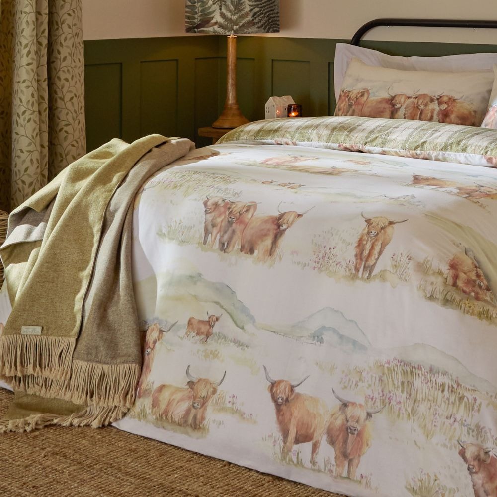 A duvet cover set featuring a hill scene print with highland cows