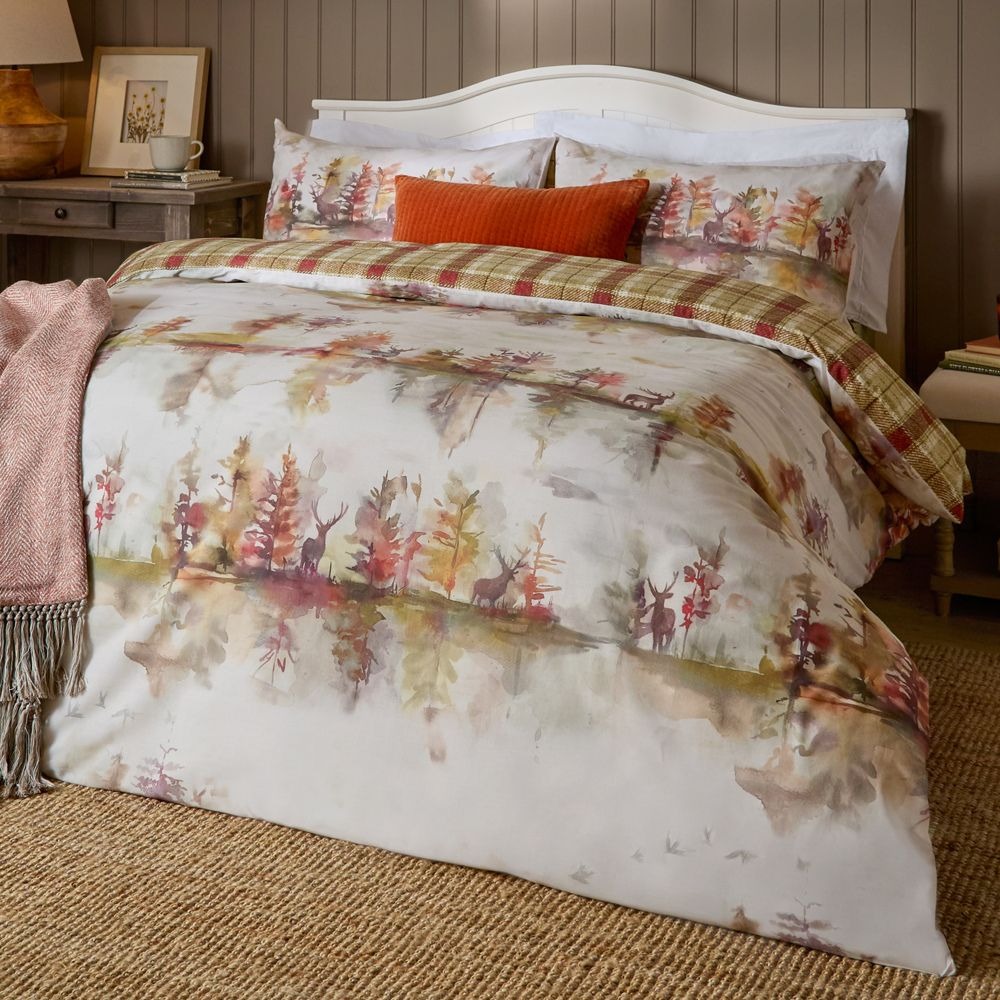 A duvet cover set with a printed hazy woodland scene with a stag, and a reverse tartan print on the other side