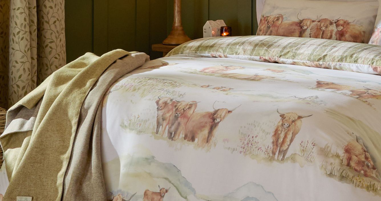 A cattle duvet cover set with green reverse tartan and a green throw at the end of the bed