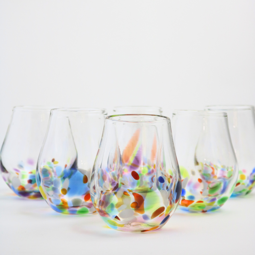 Stemless wine glasses with a colourful base arranged in a triangle.