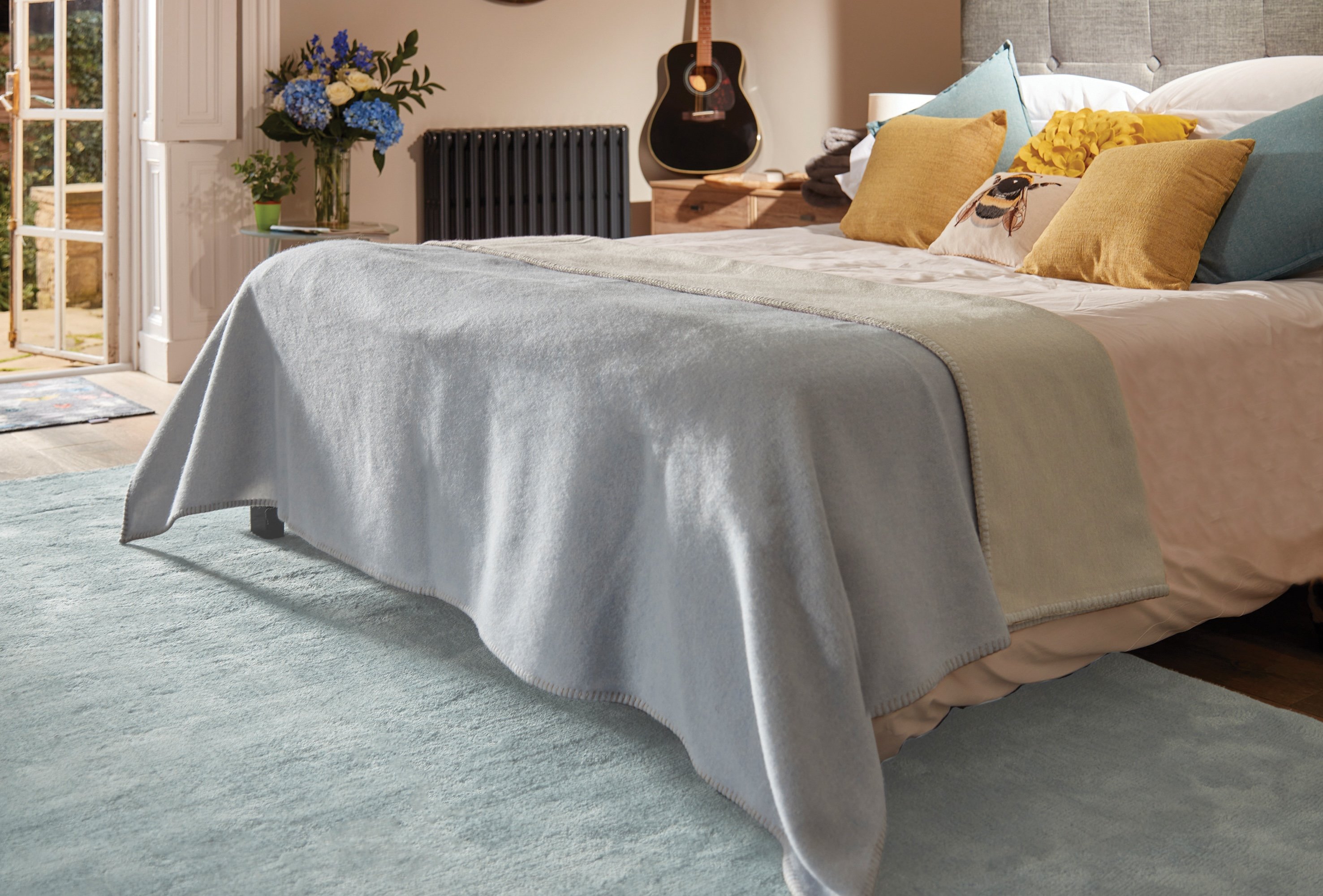 A bedroom with a large blue rug under a bed