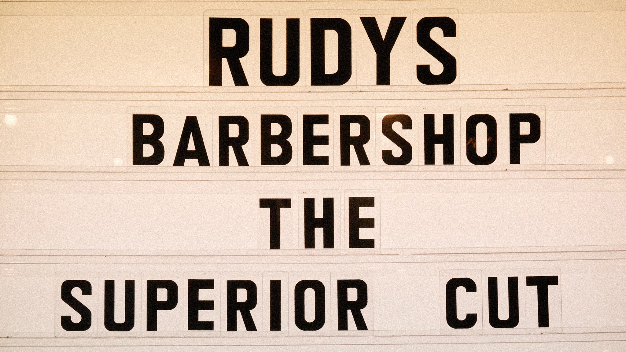 A sign that reads, "Rudy's Barbershop the superior cut"