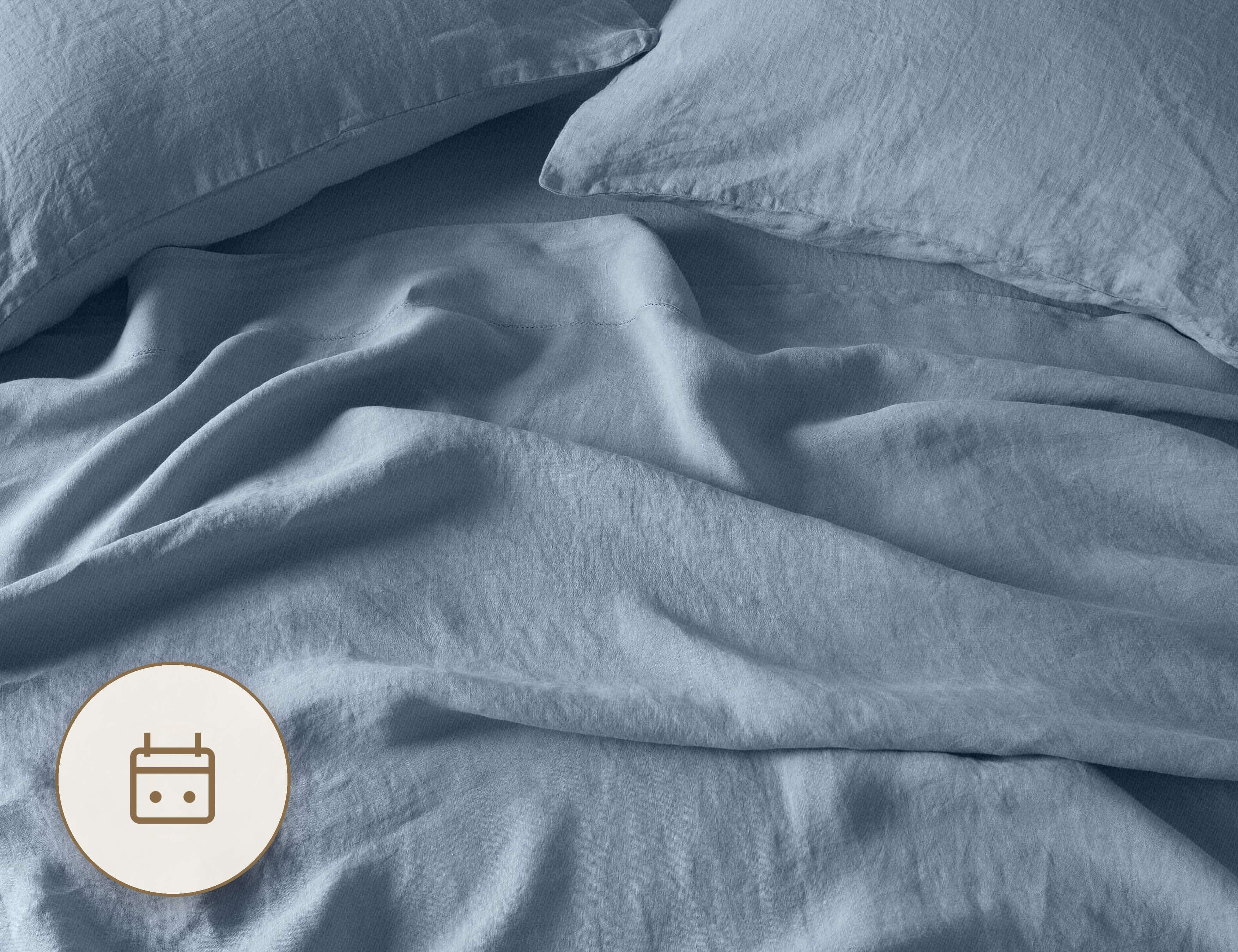 Rumpled French blue linen sheets and pillows on a made bed