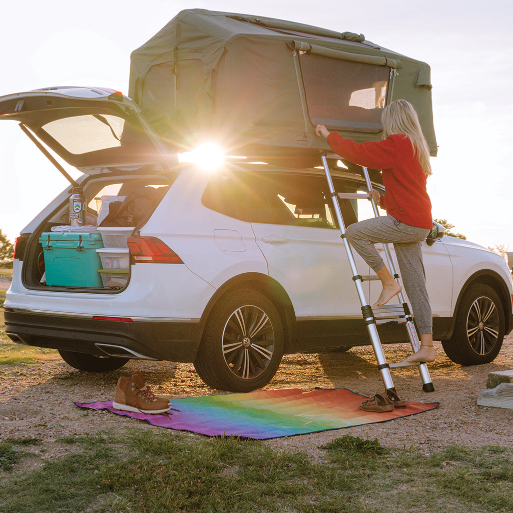A person uses the Rumpl Everywhere Mat as a water, dust, and mud repelling layer under their car awning - the perfect camper van mat!