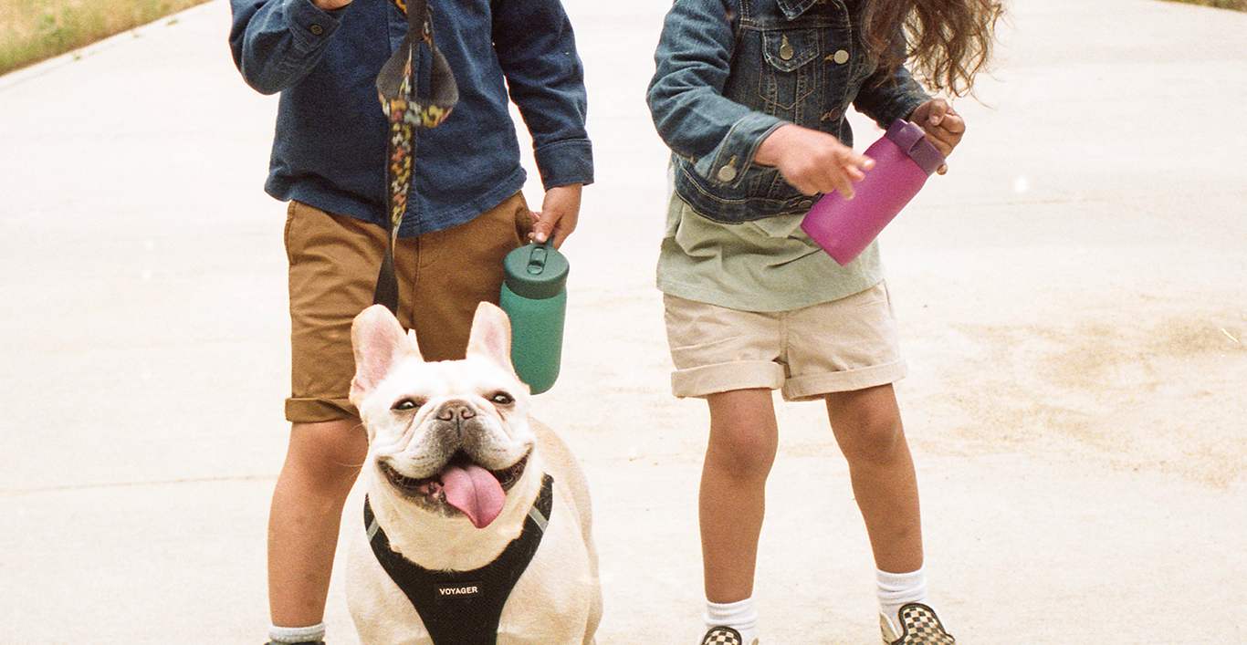  Two children holding the PLAY tumbler and a dog 