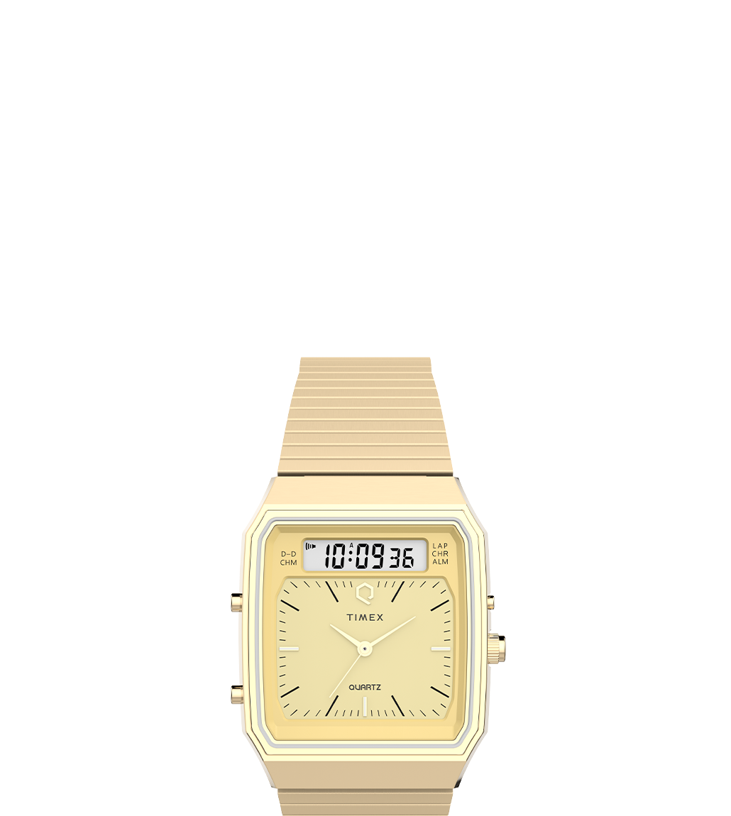 A gold-tone Q Timex® 1982 Ana-Digi Reissue watch with a champagne-colored dial, featuring a hybrid analog and digital display. The watch has a rectangular case and a flexible stainless steel bracelet, embodying a retro-inspired design.