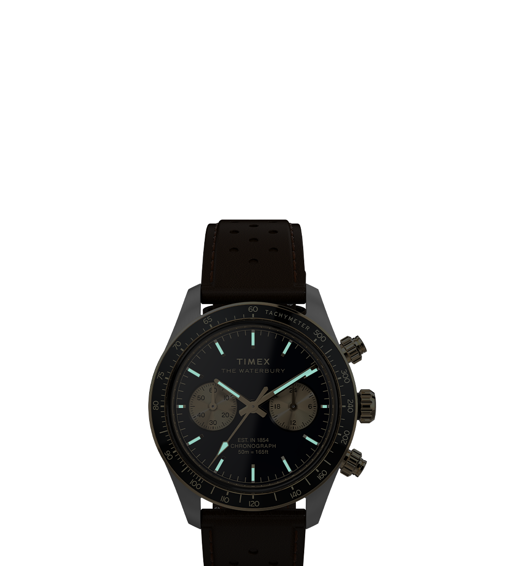 A full view of the Timex Waterbury Heritage Chronograph, featuring a black dial with gold subdials, a tachymeter scale, and a perforated brown leather strap. The vintage-inspired design blends elegance with sporty functionality.