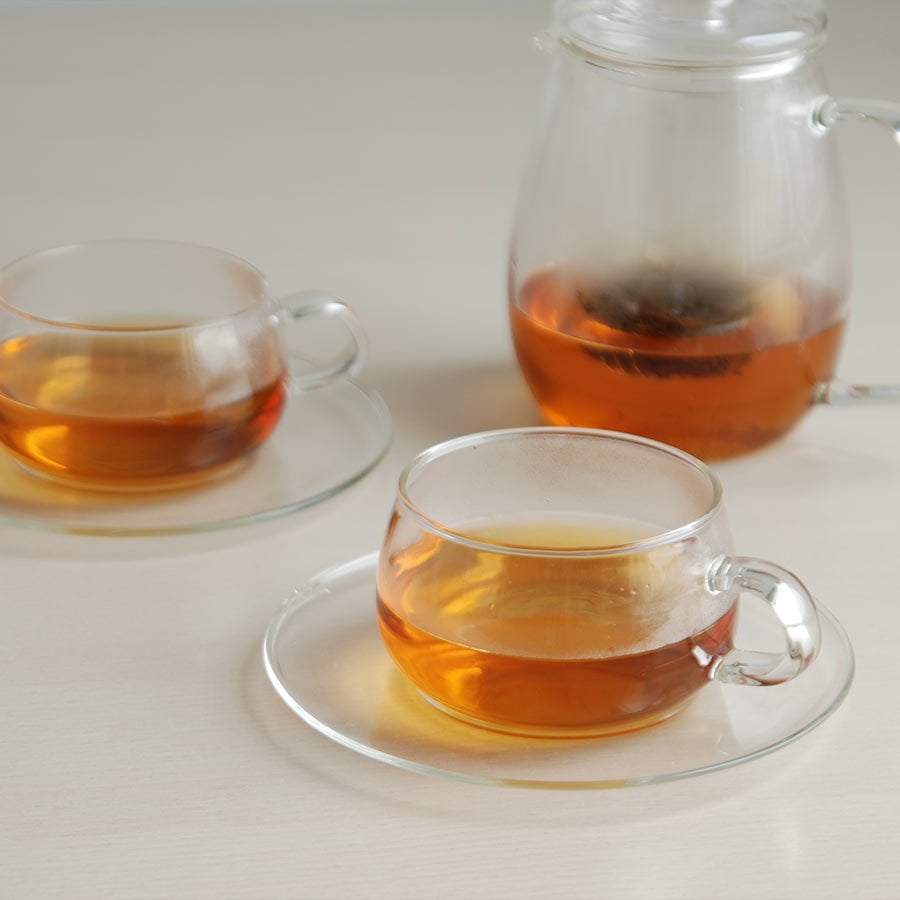 Deux UNITEA tasses et soucoupes avec du thé à l'intérieur et le UNITEA théière avec du thé