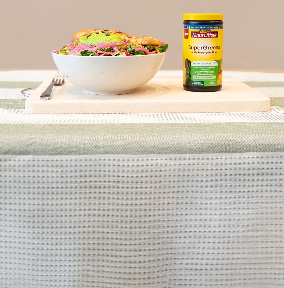 Salmon avocado bowl with Nature Made SuperGreens with Prebiotic Fiber Powder Drink Mix on a chopping board.