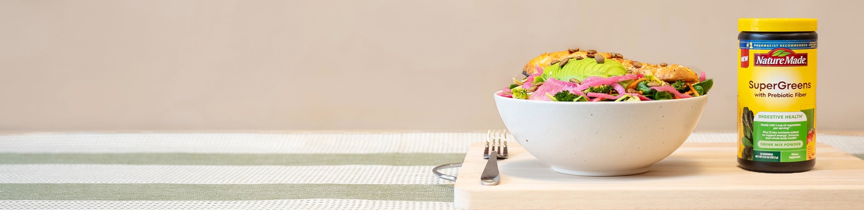 Salmon avocado bowl with Nature Made SuperGreens with Prebiotic Fiber Powder Drink Mix on a chopping.
