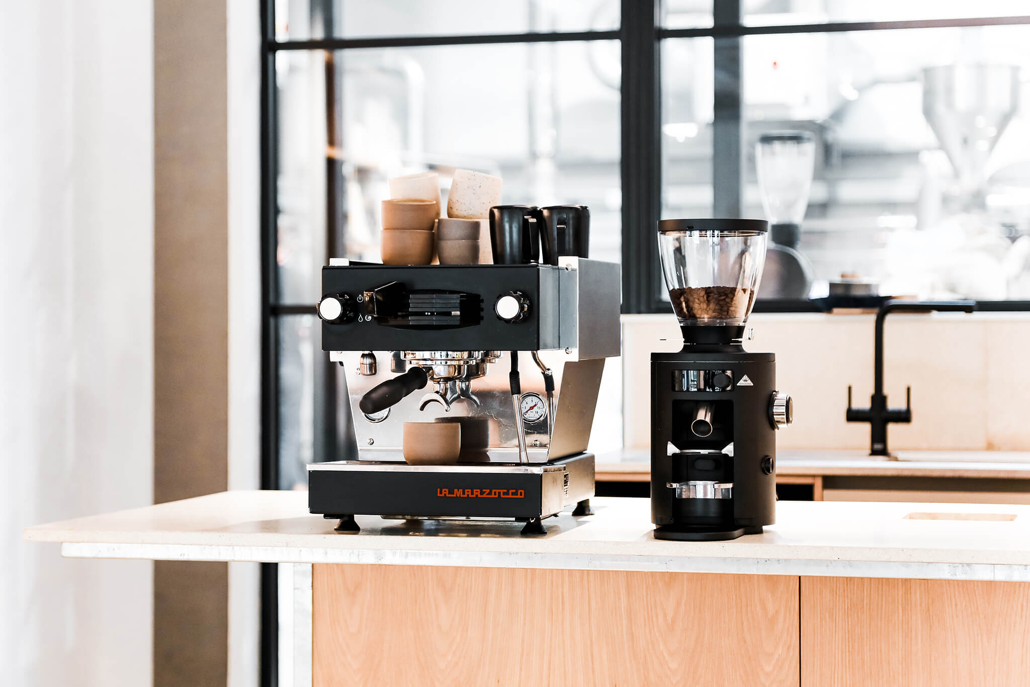 A home espresso machine and home coffee grinder sitting on a bar