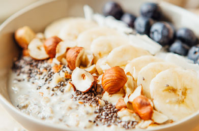 Closeup of bowl of oatmeal made with Navitas Essential Blend Vanilla & Greens and topped with fruit and fresh ingredients
