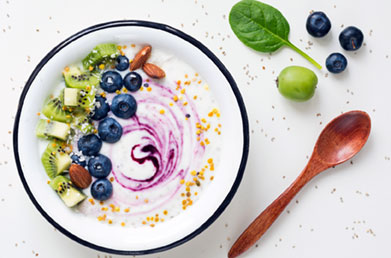 Bowl of yogurt and fruit swirled with Navitas Organics Acai Powder