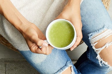 Hands holding mug of matcha latte made with Navitas Matcha Powder