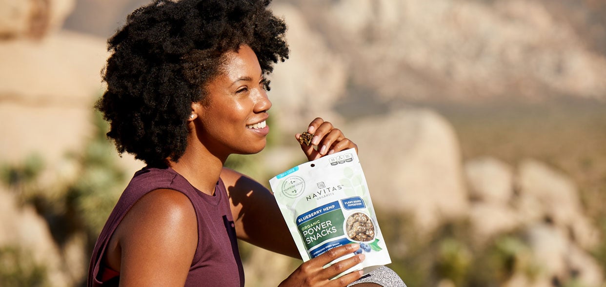 Person eating a package of Navitas Powder Snacks Blueberry Hemp