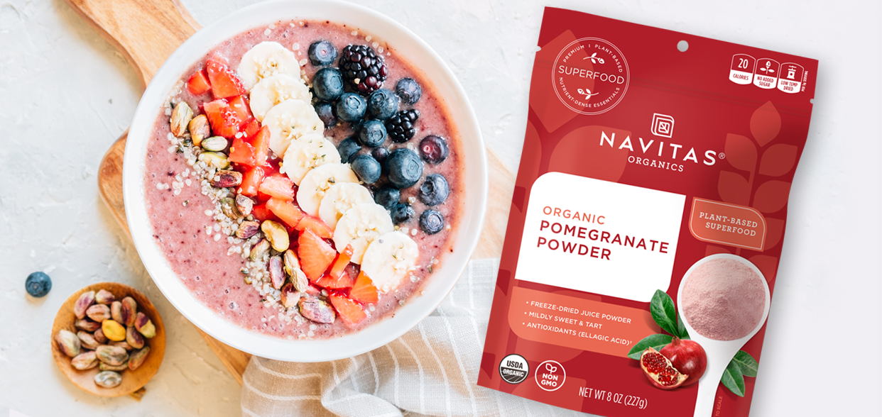 Smoothie Bowl topped with fresh fruit sitting alongside a bag of Navitas Pomegranate Powder.