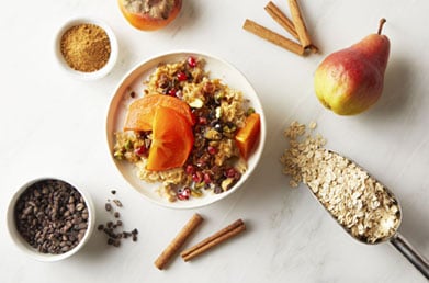 Bowl of yogurt made with Navitas Goldenberries topped with grains and fruit and surrounded by fresh ingredients