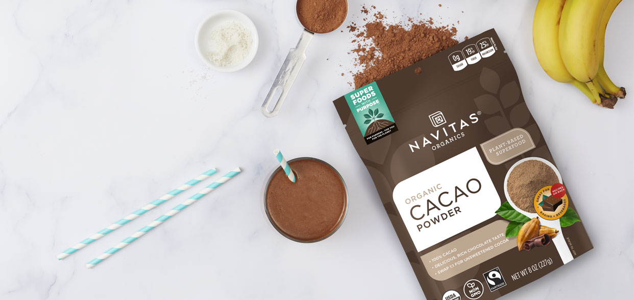 Glass of chocolate drink made with Navitas Cacao Powder on a counter next to fresh ingredients