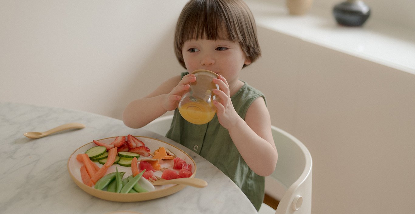  Toddler drinking out of the BONBO straw cup with BONBO plate filled with fruits and vegetables  