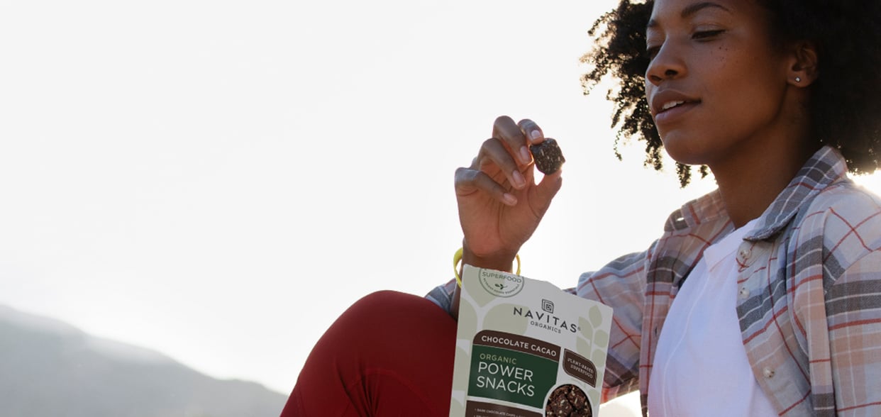 Woman snacking on Navitas Chocolate Cacao Power Snacks outside