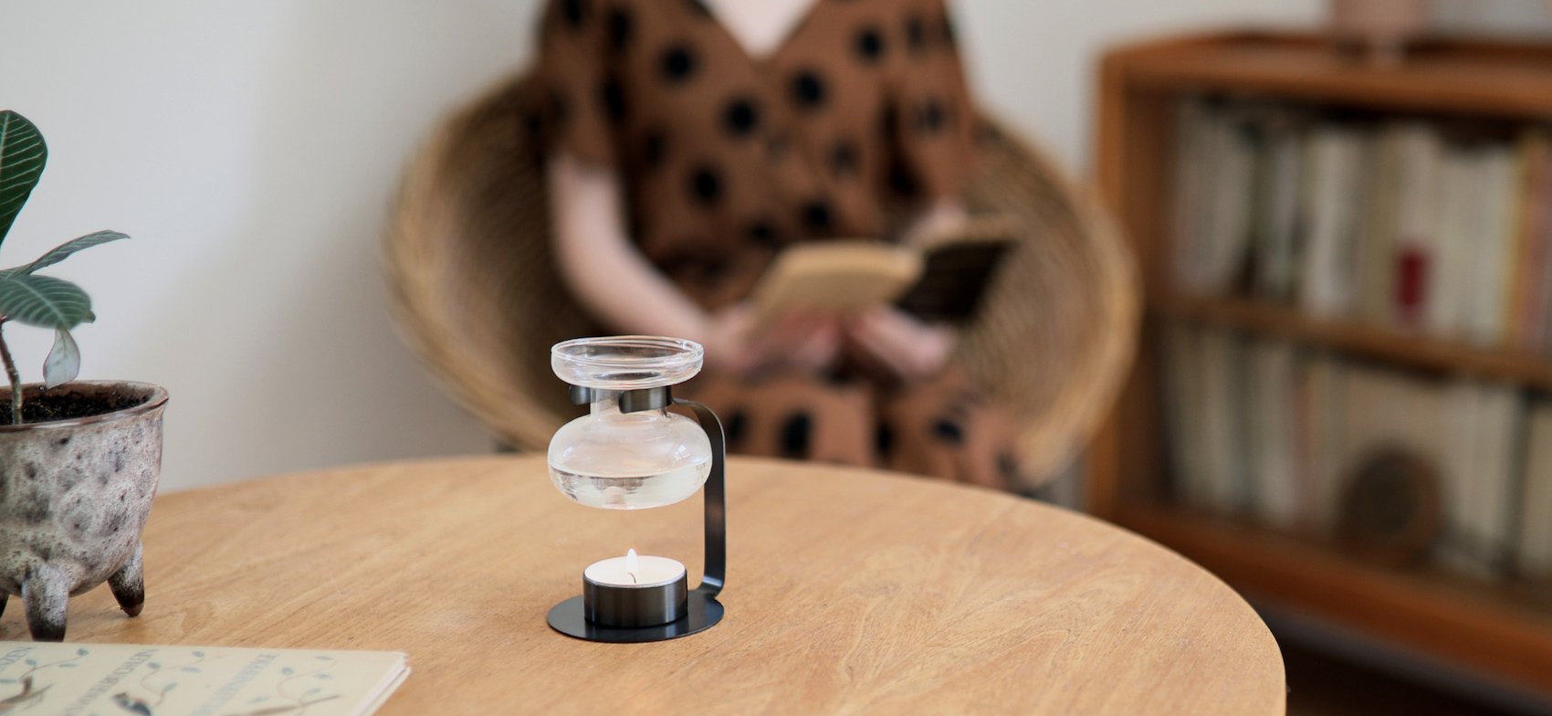 AROMA OIL WARMER black on a table with person reading in the background  