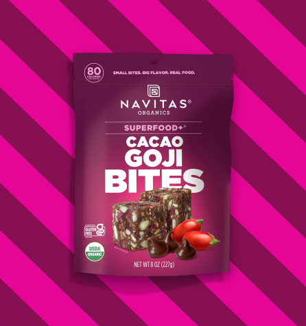 A package of Navitas Organics Superfood+ Cacao Goji BITES on a two-toned pink striped background.