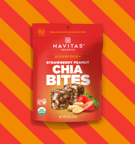 A package of Navitas Organics Superfood+ Strawberry Peanut Chia BITES on a two-toned orange striped background.
