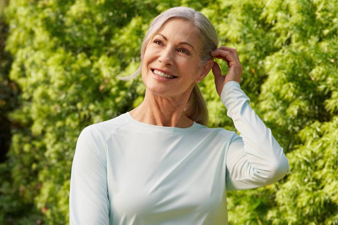 Person outdoors wearing a long‑sleeve top with trees in the background