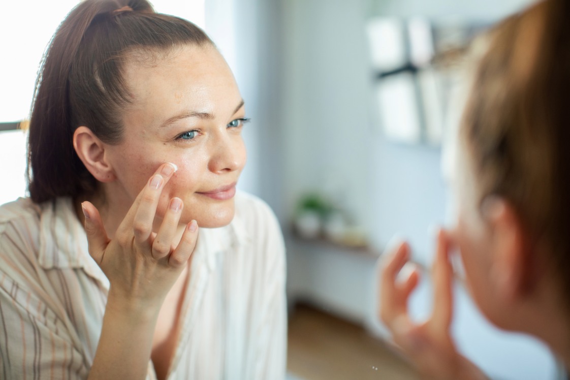 Person touching face while looking into a bathroom mirror