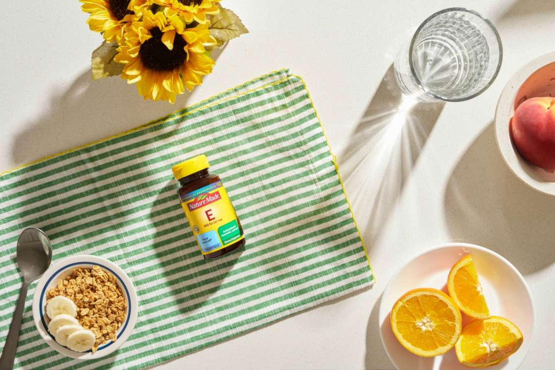 Nature Made Vitamin E 400 IU bottle on a green checkered cloth with breakfast items
