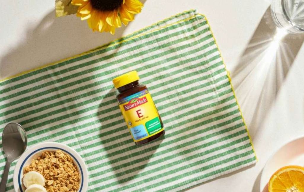 Nature Made Vitamin E 400 IU bottle on a green checkered cloth with breakfast items