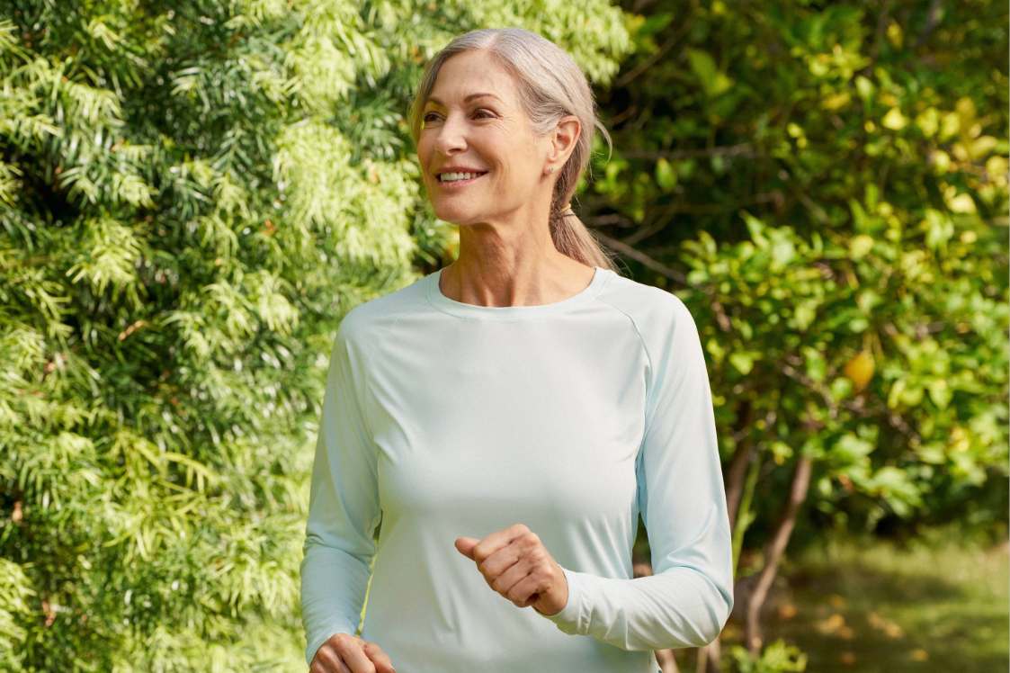 Person jogging outdoors along a green, leafy path
