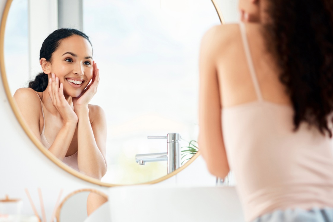 Person touching face while looking in a bathroom mirror