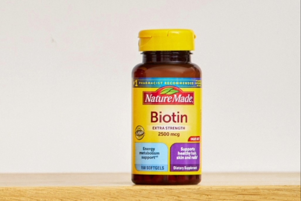 Nature Made Biotin 2500 mcg supplement bottle on a wooden surface.