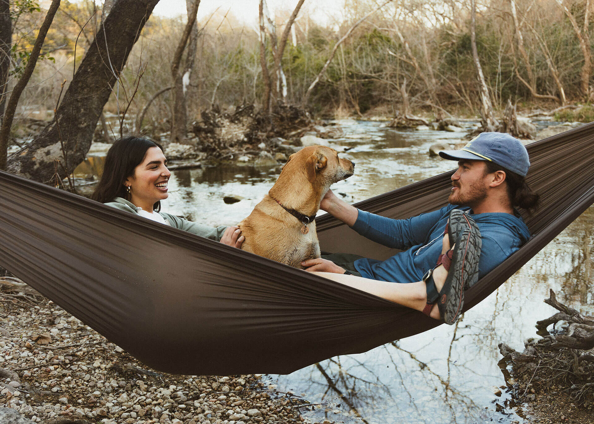 Man, woman, and dog sitting in Kammok Roo Double XL in Granite Gray.