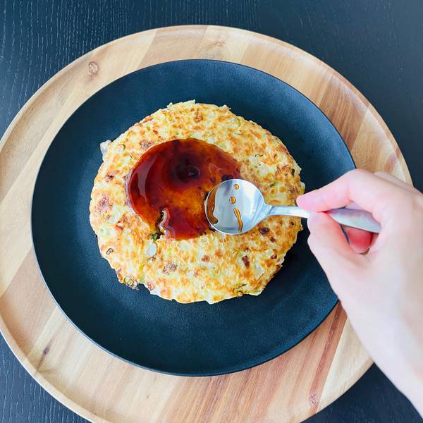 spooning okonomiyaki sauce 