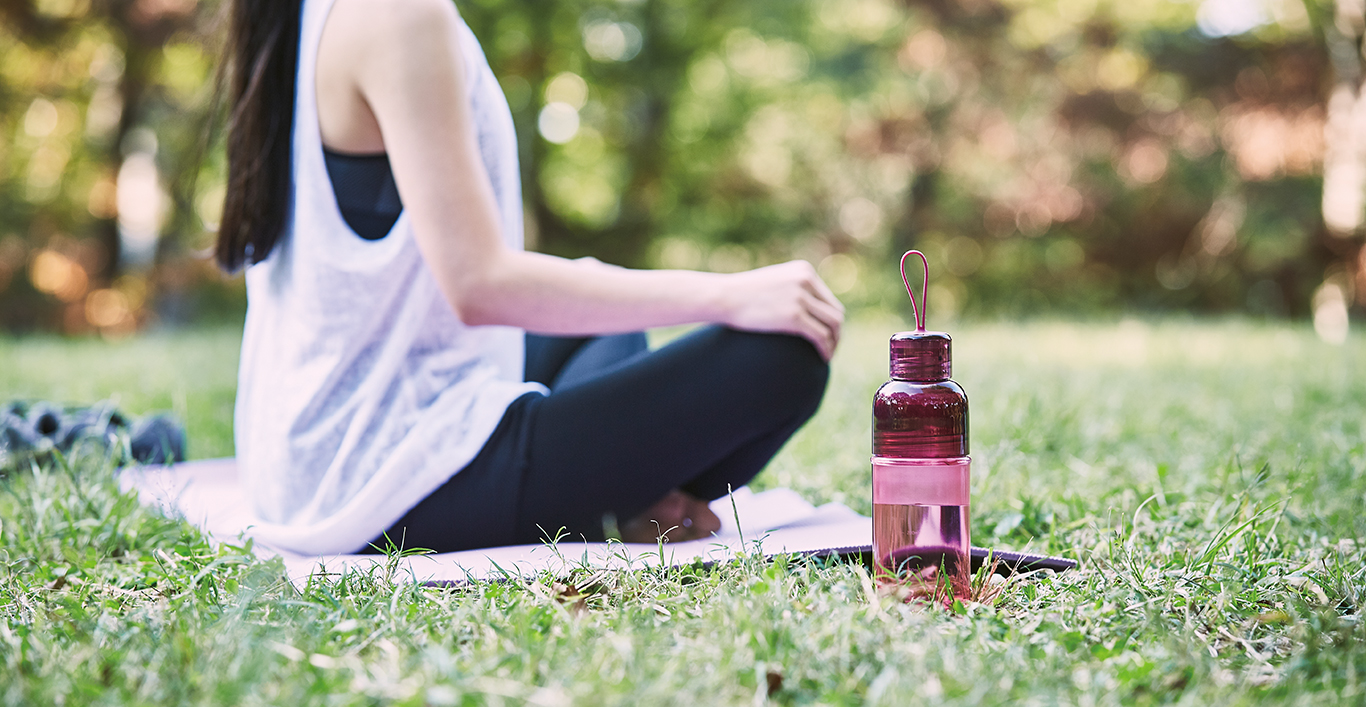  WORKOUT bottle magenta next to person sitting on the grass  
