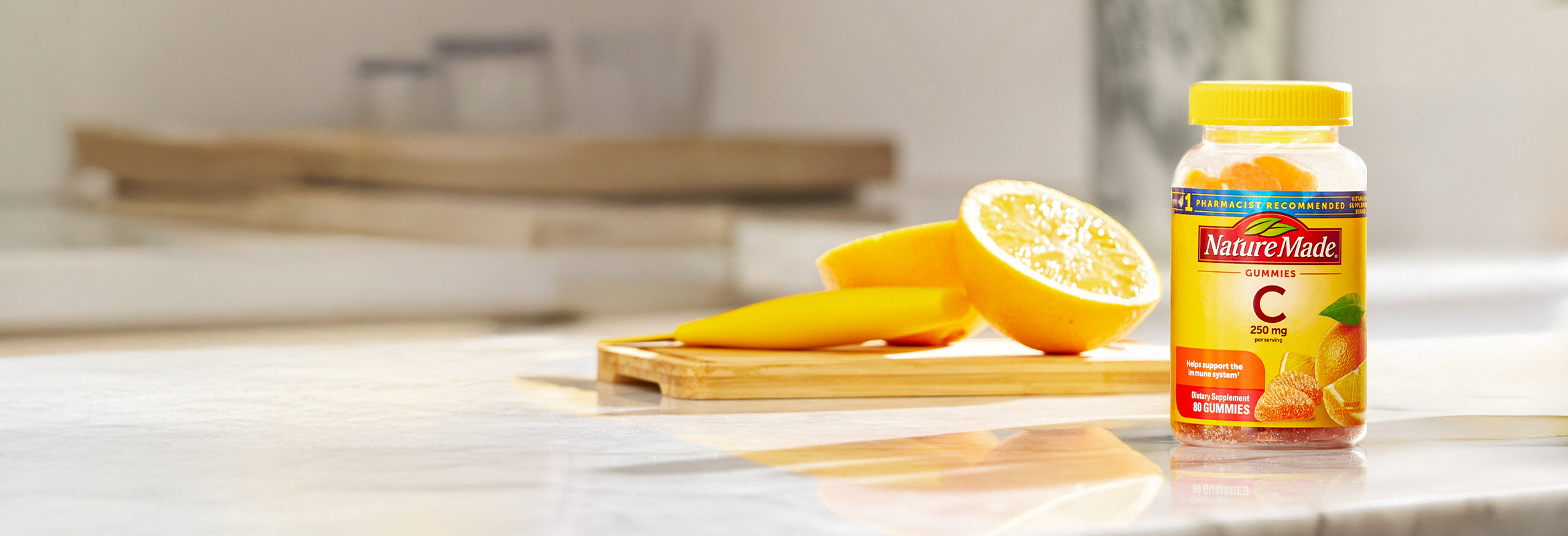 Vitamin C 250 mg gummies on a kitchen counter with slices of oranges.