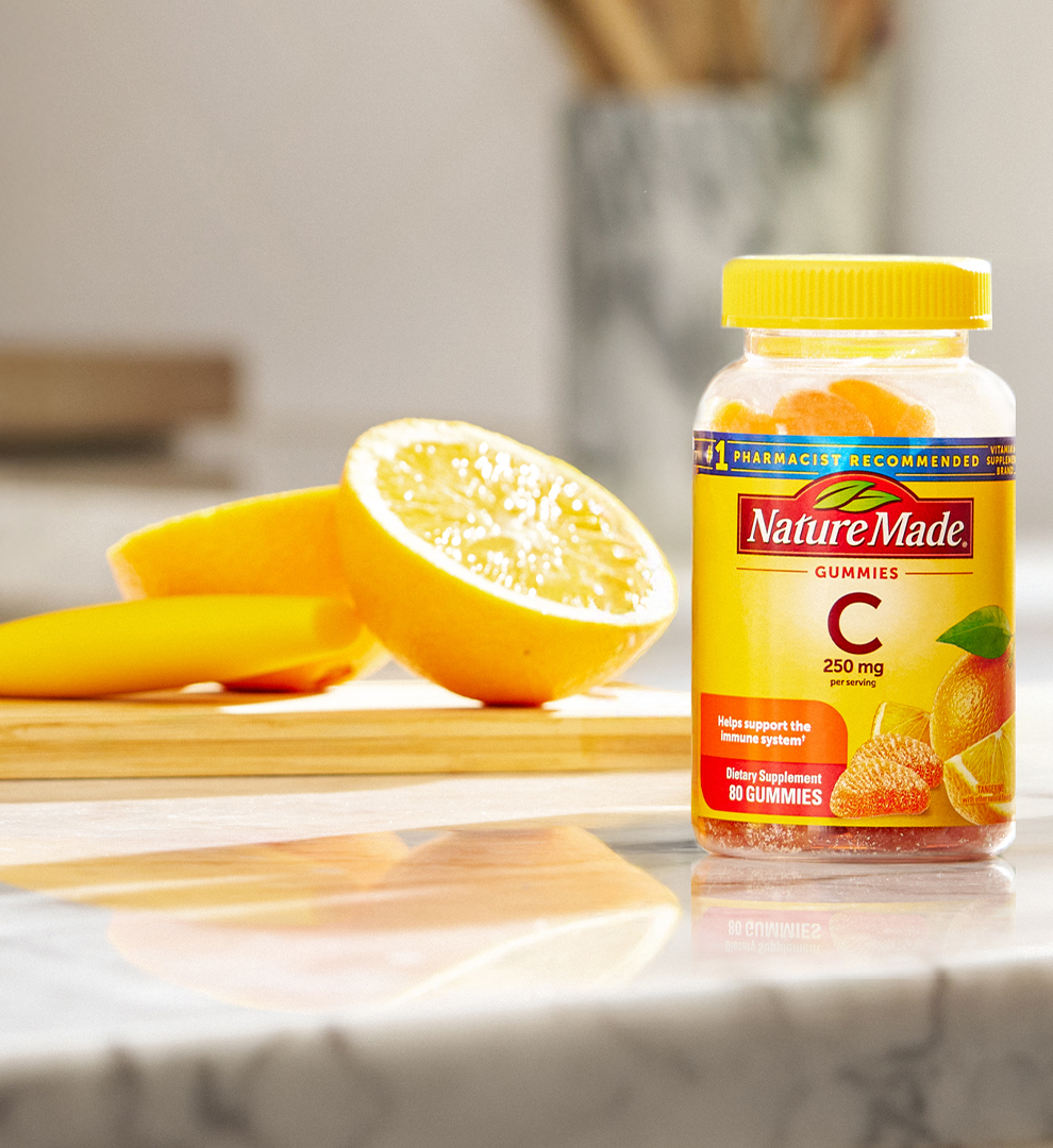 Vitamin C 250 mg gummies on a kitchen counter with slices of oranges.