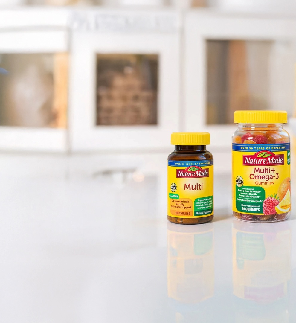 Nature Made Multivitamin tablets and Multi+Omega‑3 gummies displayed on kitchen counter.