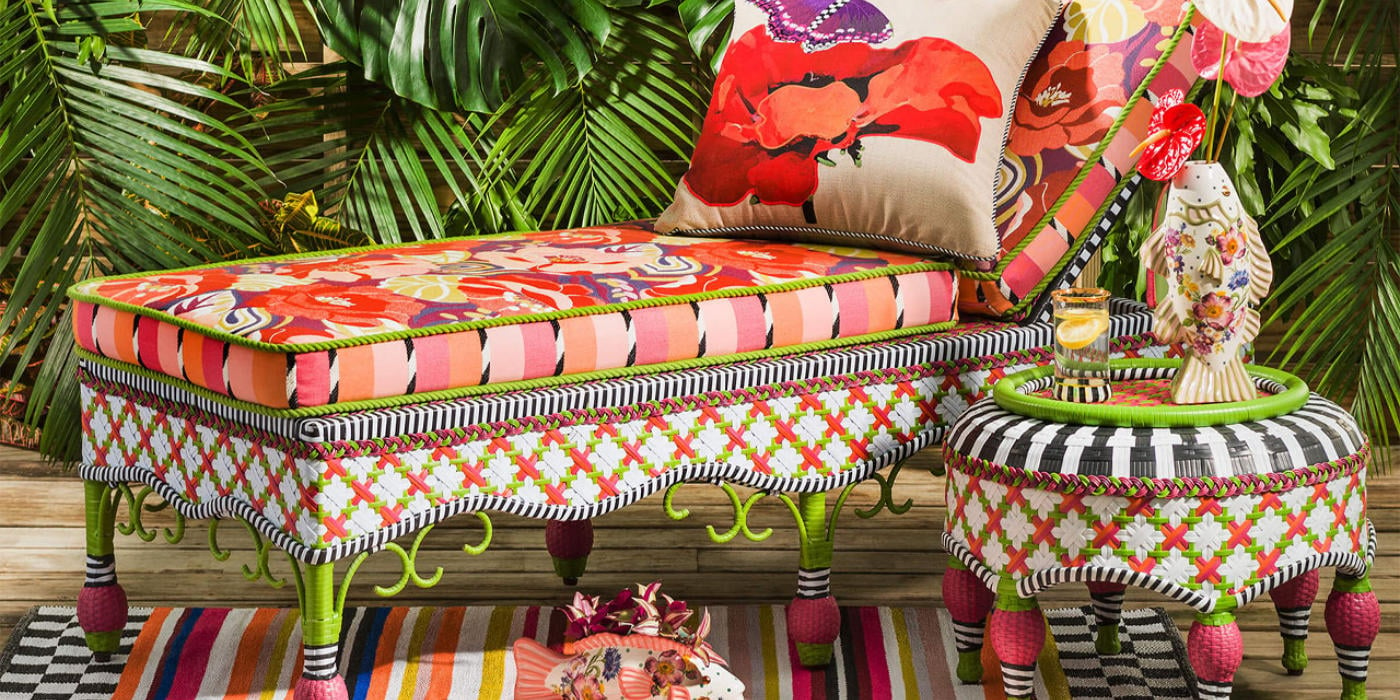 A patio furniture set up, vibrant colors, red and greens, some colorful pillows, snd plants on the background