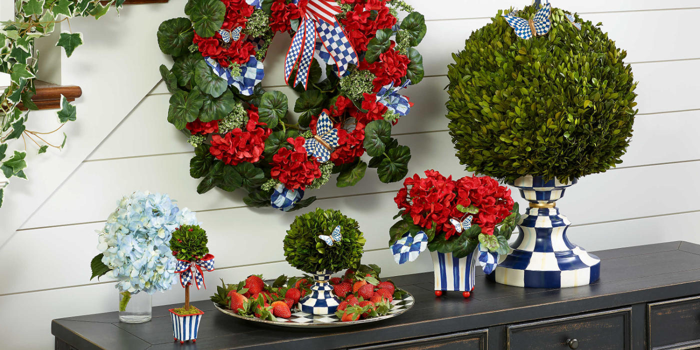 A console table, with holiday decor items on it, courtly check patterns, red bows, and green plants