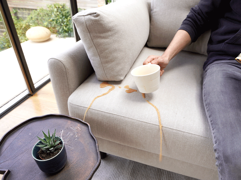Tea being split onto Model 04 Sofa Bed in Pumice Linen to demonstrate stain resistance
