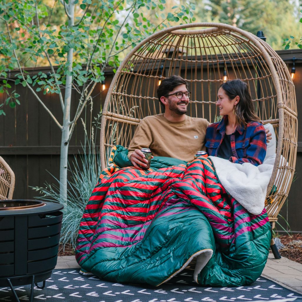 A couple relaxes on their back patio with a super soft puffy sherpa blanket around their laps.