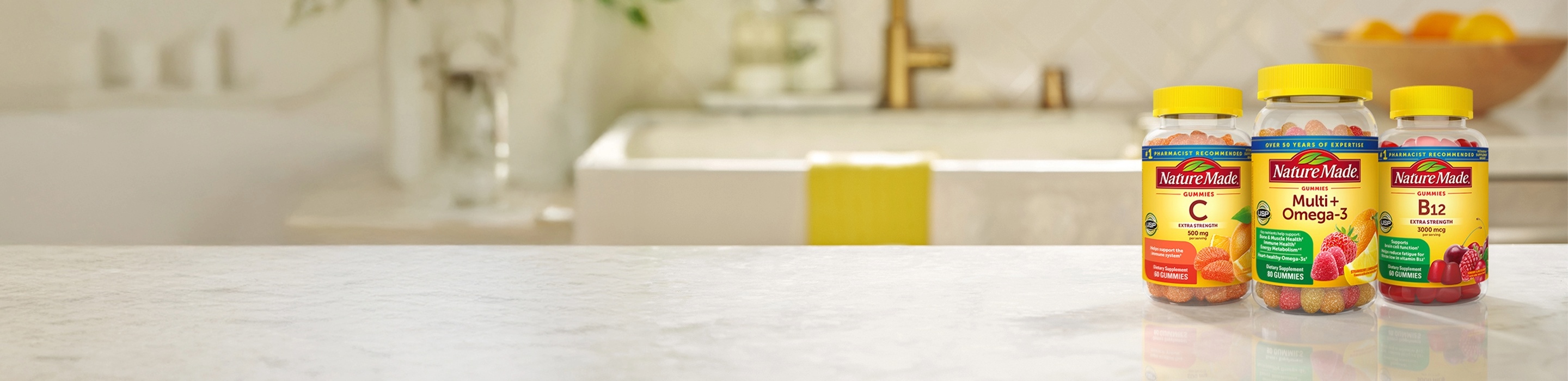 Nature Made gummy vitamins including Vitamin C, Multi+Omega‑3, and B12 bottles on a kitchen counter.
