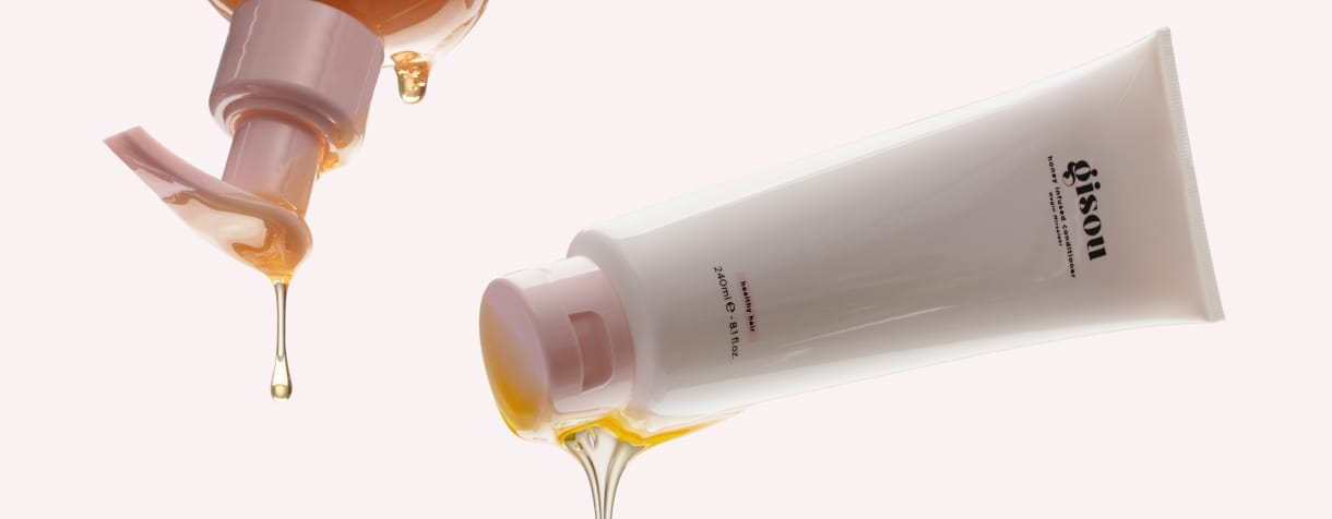 Honey Infused Shampoo & Conditioner floating in air with honey dripping