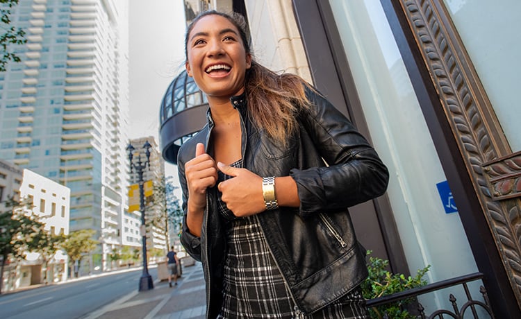 Young woman in the city wears The Confidante watch in All Gold. 