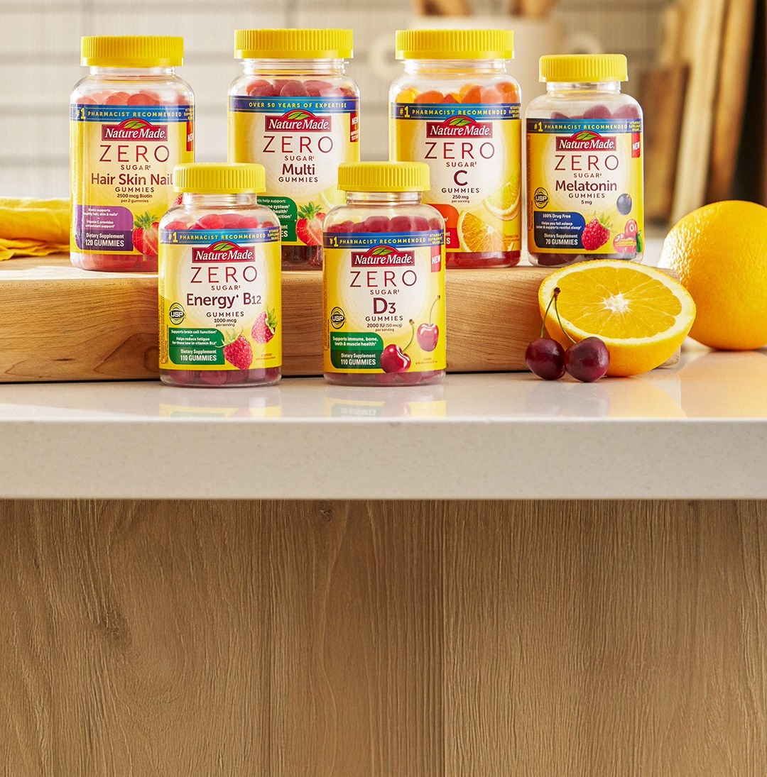 Nature Made Zero Sugar gummies displayed on kitchen counter with oranges and cherries.